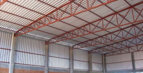 Estrutura interna de galpão com calhas metálicas e serralheria industrial